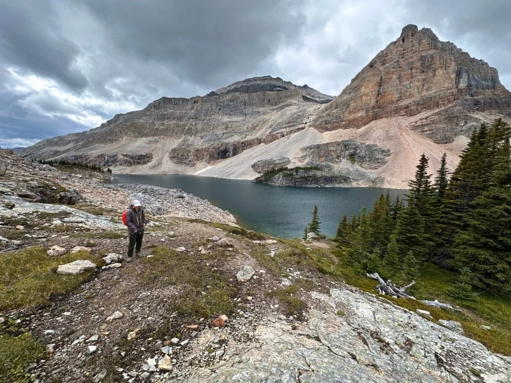 A hiker stands near the shore of Mummy Lake. 