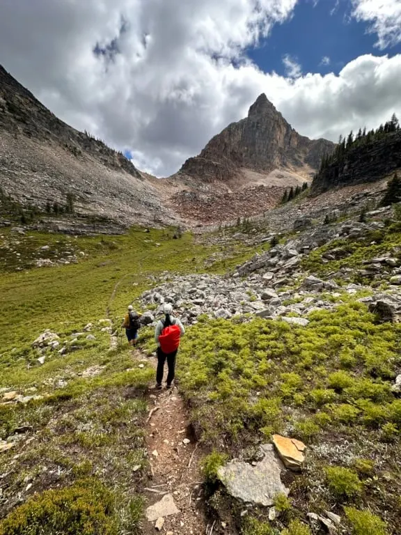 Two hikers in an alpine meadow near Mummy Lake