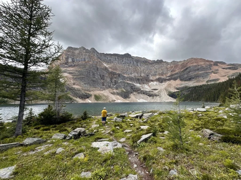 A hiker stands on the shore of Scarab Lake