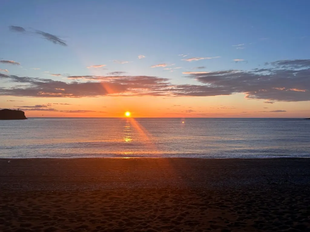 The sun setting into the ocean in Trout River, Newfoundland