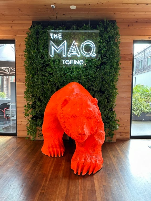 A giant orange bear sculpture emerges from a wall underneath a sign reading "The MAQ Tofino" at the Bear Bierhouse