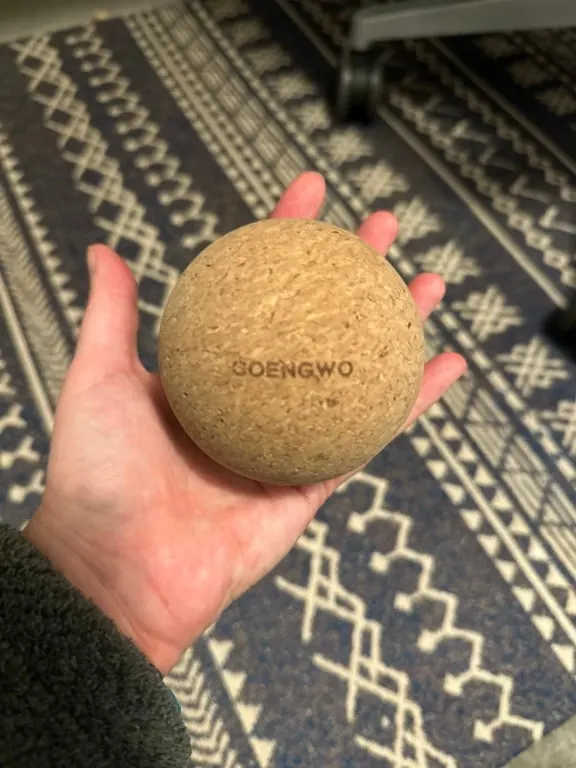 A close up of a peron's hand holding a cork massage ball