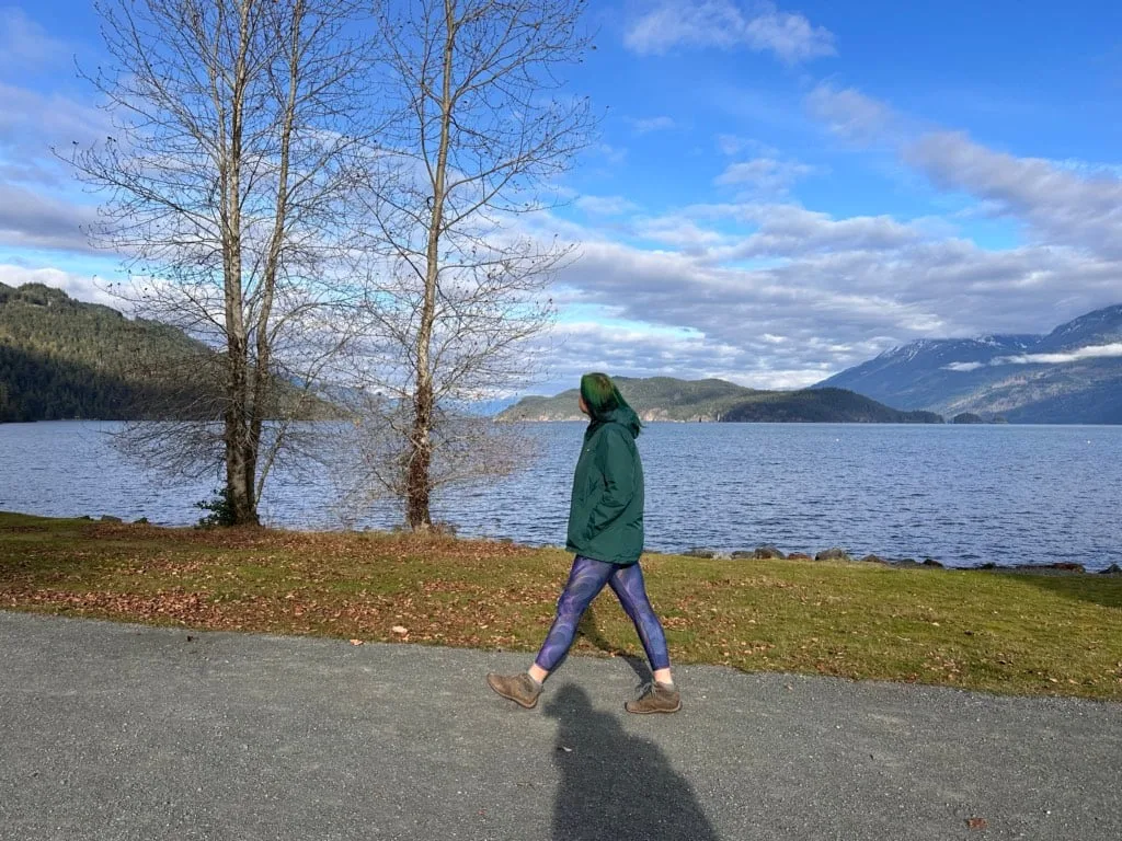 A woman in a green coat walking along the Esplanade in Harrison Hot Springs