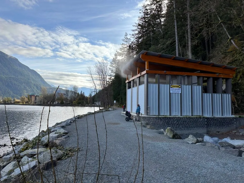 Steam escapes from a roofed enclosure at the source of the Harrison Hot Springs. The enclosure is at the edge of the lake. 