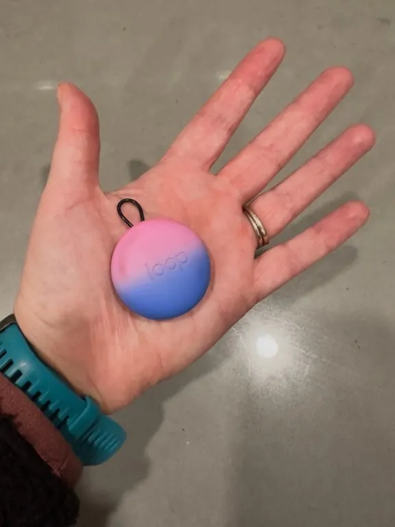 A close up of a person's palm holding the case for Loop ear plugs