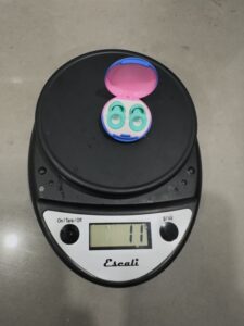 Loop ear plugs in a case on a kitchen scale. The scale reads 11 g.