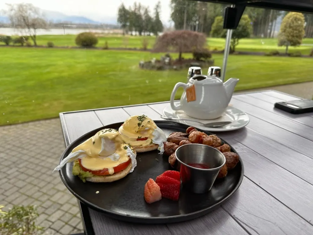 Eggs Benedict on a table with a view of the Harrison River