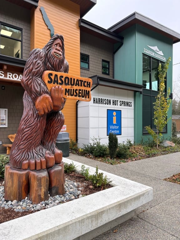 A Sasquatch statue holding a sign that says Sasquatch Museum in Harrison Hot Springs