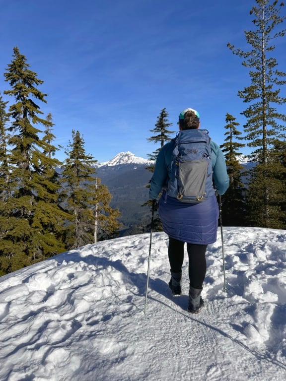 A woman wearing a blue insulated skirt walks in the snow