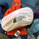 A pile of MEC Brand gear displaying various logos dating from the present back to over 20 years ago.