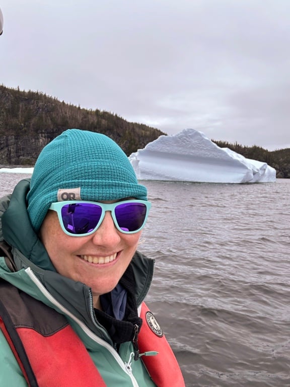 A woman takes a selfie in front on an iceberg