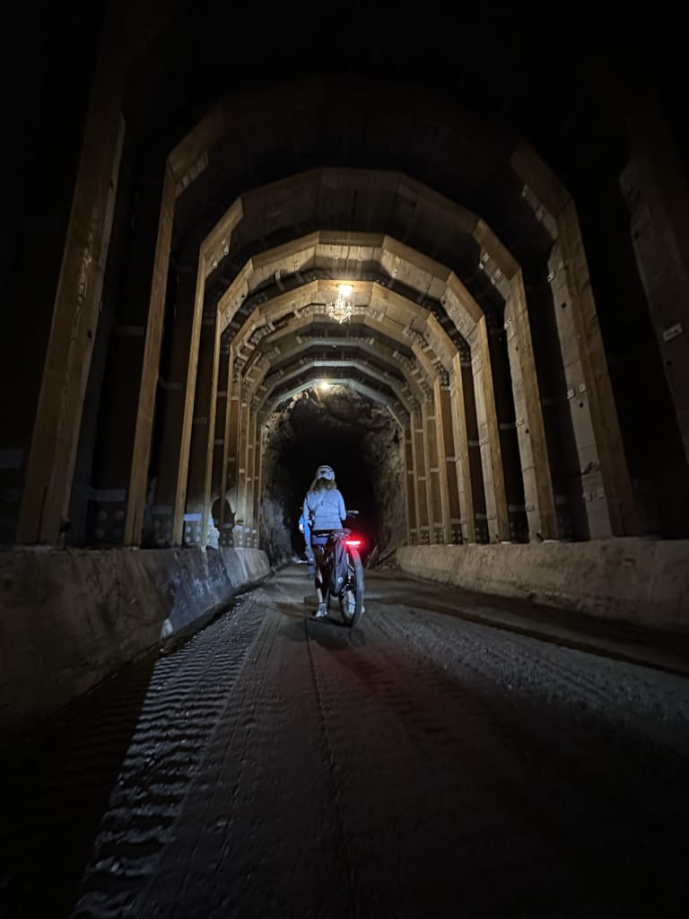 A woman rides a bike through Adra Tunnel in Penticton