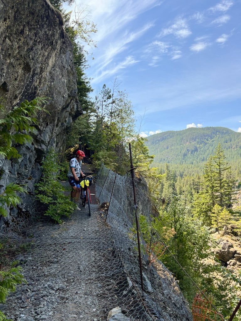 A cyclist crosses the mesh catwalk section in Cheakamus Canyon.