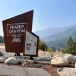 Sign welcoming people to the Fraser Canyon with mountains in the background