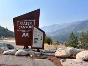 Sign welcoming people to the Fraser Canyon with mountains in the background