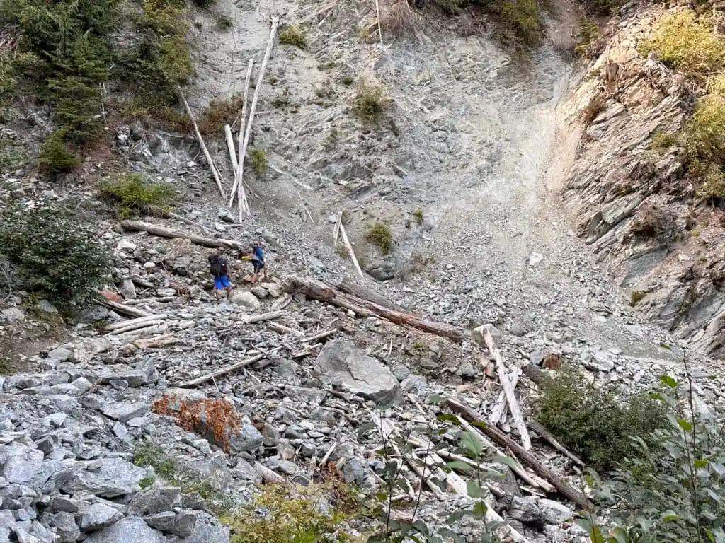 Hikers crossing the Harmony Creek washout on the Singing Pass Trail in Whistler