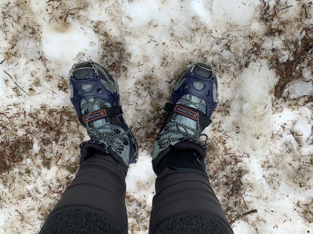 A close up of a hiker wearing Hillsound Trail Crampon Ultras in dirty snow
