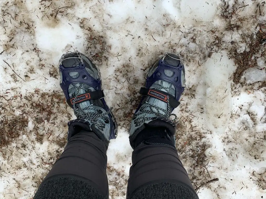 A close up of a hiker wearing Hillsound Trail Crampon Ultras in dirty snow