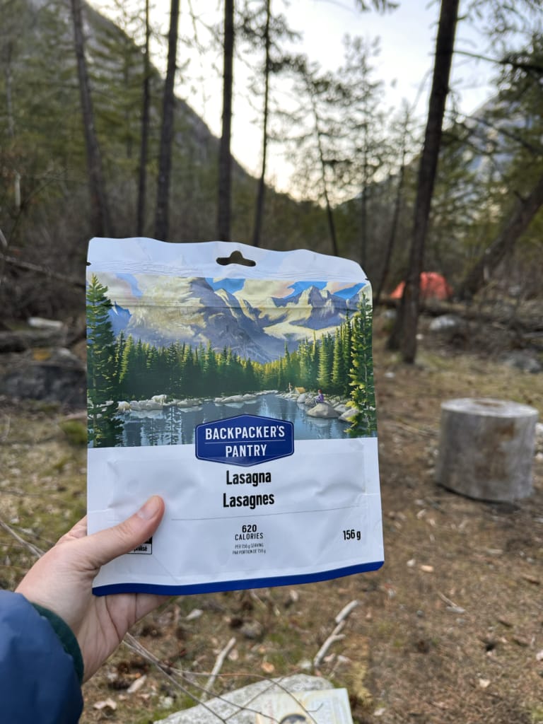 A packet of Backpacker's Pantry Lasagna being held up by a hiker's hand