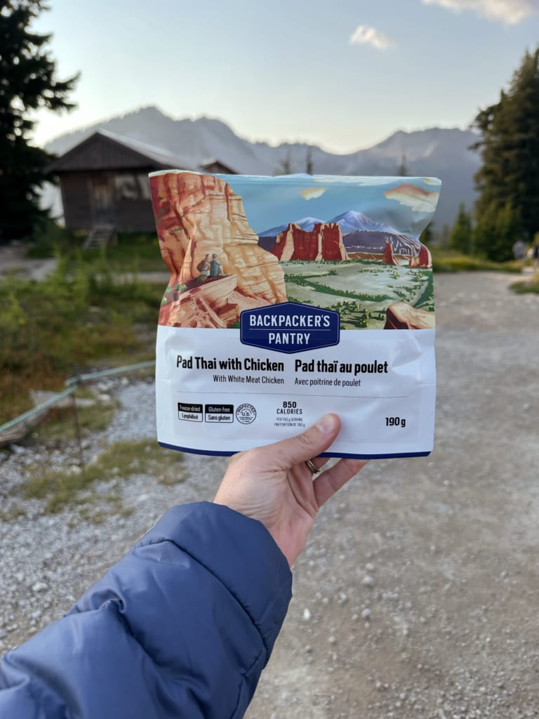 A hiker holds a package of Backpacker's Pantry Pad Thai With Chicken