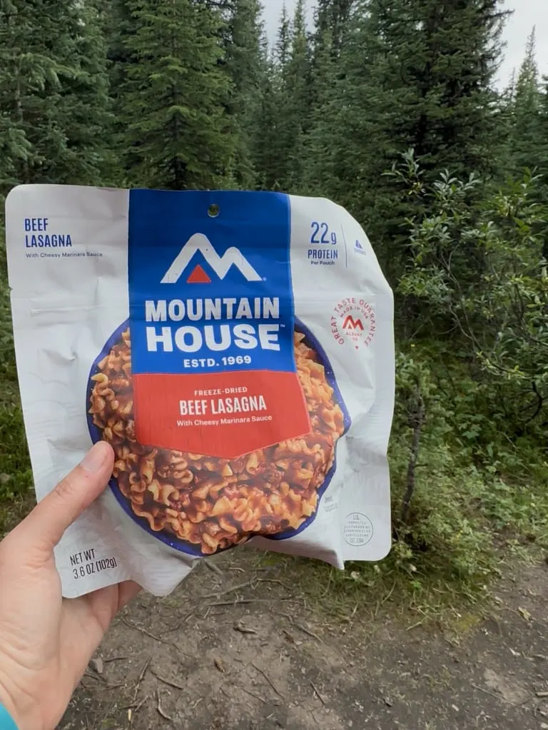A hiker holds a package of Mountain House Beef Lasagna