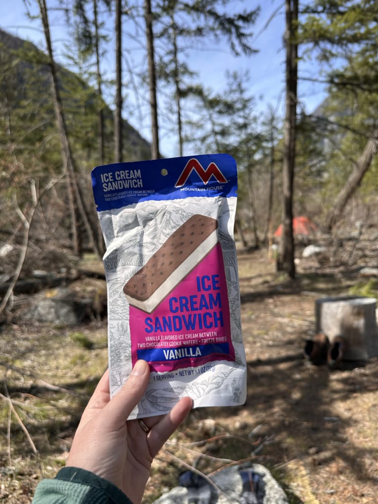 A hiker holds a package of Mountain House Vanilla Ice Cream Sandwich