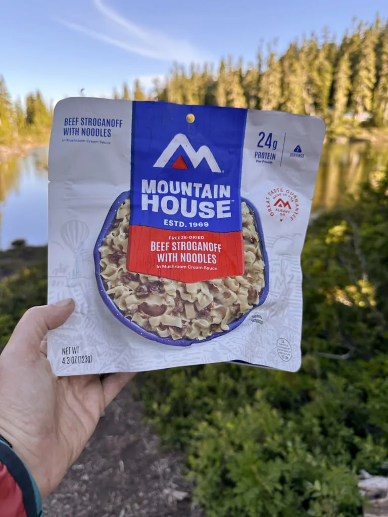 A hiker holds a package of Mountain House Beef Stroganoff
