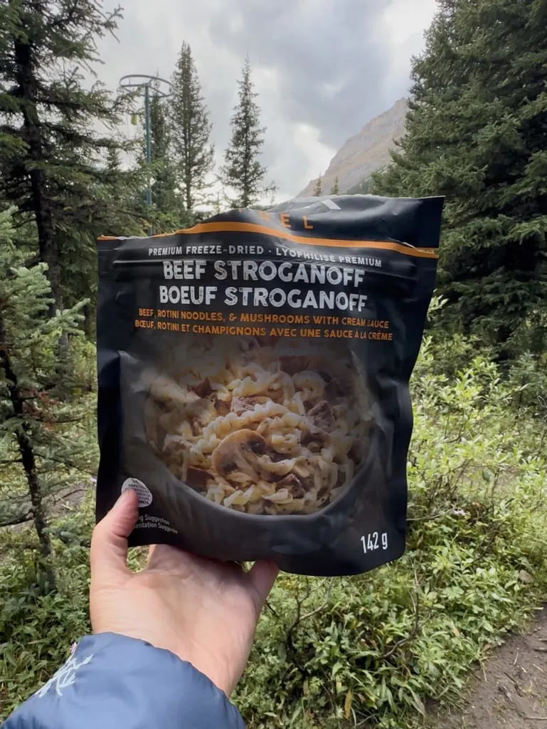 A hiker holds a package of Peak Refuel Beef Stroganoff
