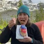 A hiker eats a Mountain House backpacking meal at a campsite. It is one of the best backpacking meals she reviewed.