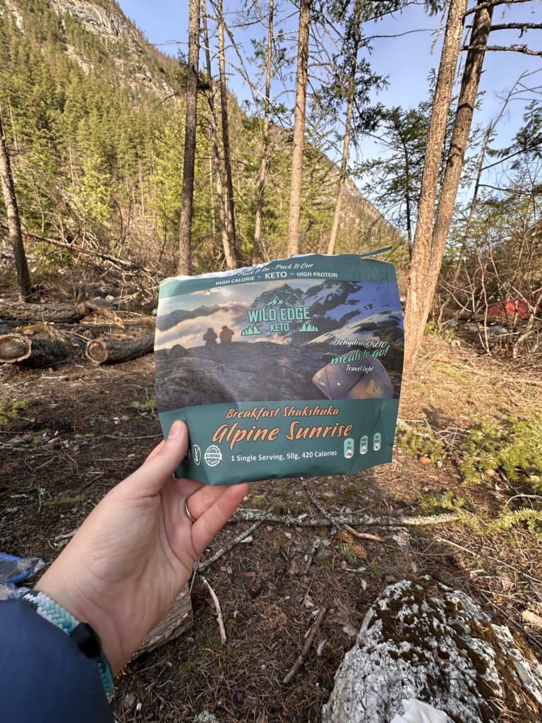 A hiker holds a pouch of Wild Edge Keto Breakfast Shakshuka