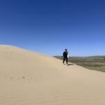 A woman walks on a sand dune at the Great Sand Hills, one of the best things to do in Saskatchewan