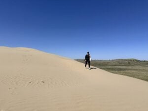 A woman walks on a sand dune at the Great Sand Hills, one of the best things to do in Saskatchewan