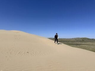 A woman walks on a sand dune at the Great Sand Hills, one of the best things to do in Saskatchewan