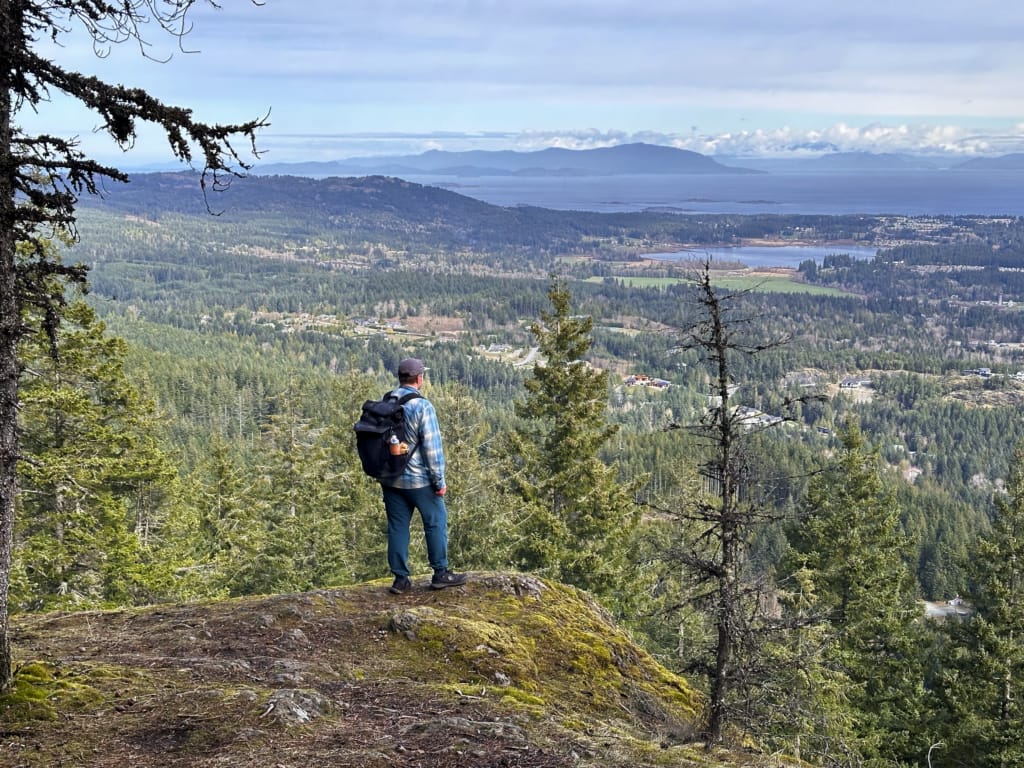 A hiker stands at a viewpoint on Mount Benson looking down on Nanaimo