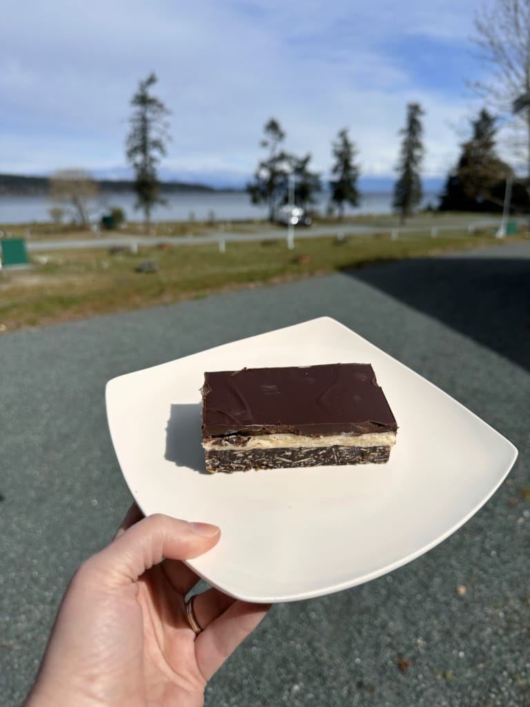 A close of a person holding a Nanaimo Bar on a plate