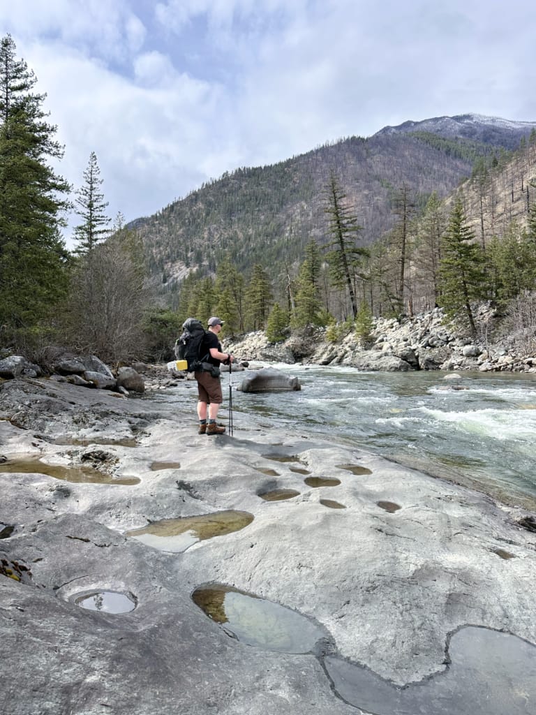 A hiker takes a break on a rock outcrop near the Stein River