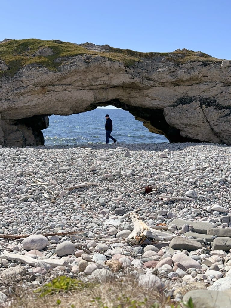 A person walks under a sea arch at Arches Provincial Park on the Viking Trail in Newfoundland