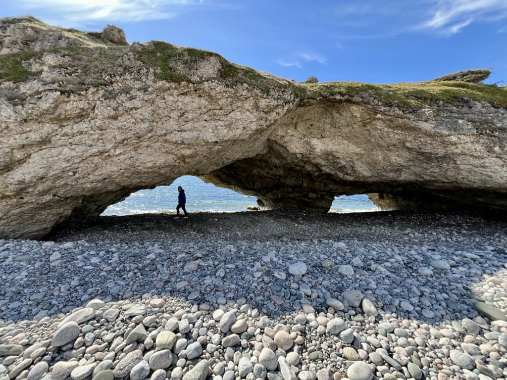A person walks under a rock arch at Arches Provincial Park on Newfoundland's Great Northern Peninsula