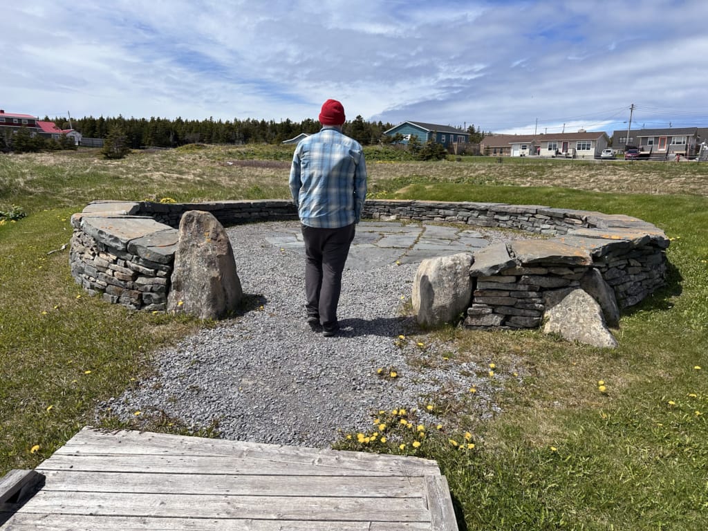 A man wearing hiking clothing walks through Port au Choix National Historic Site in Newfoundland