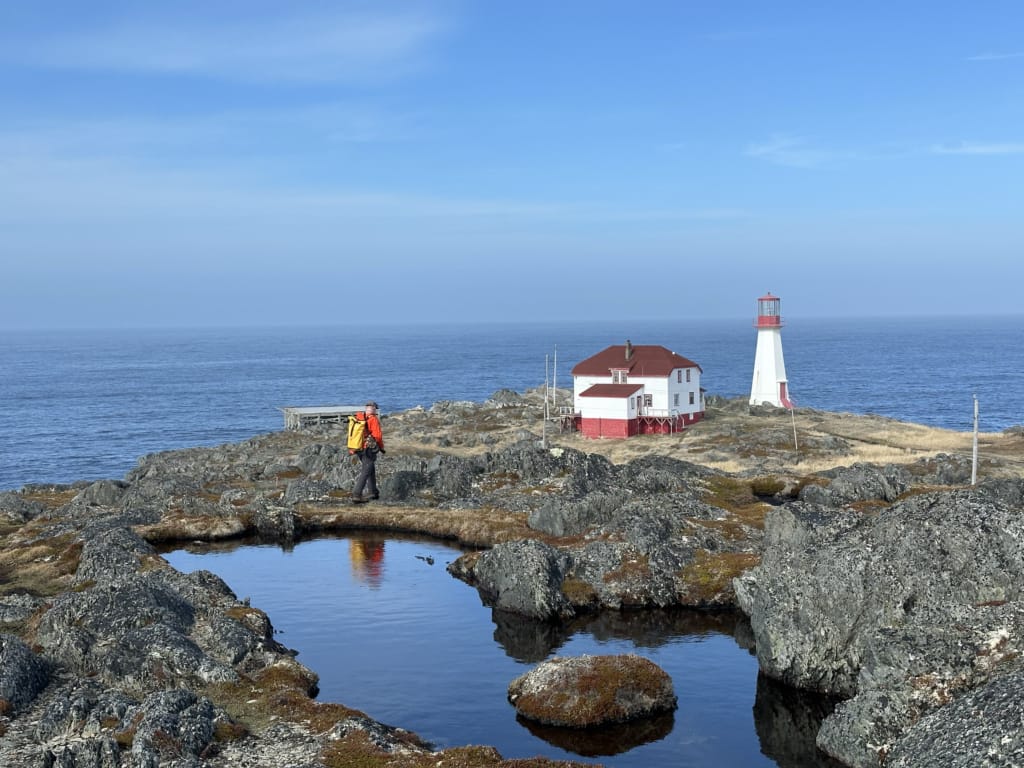 A man walks past a pond near the Quirpon Island Lighthouse