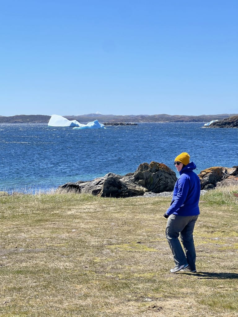 A woman poses with an iceberg in Saint Lunaire, Newfoundland