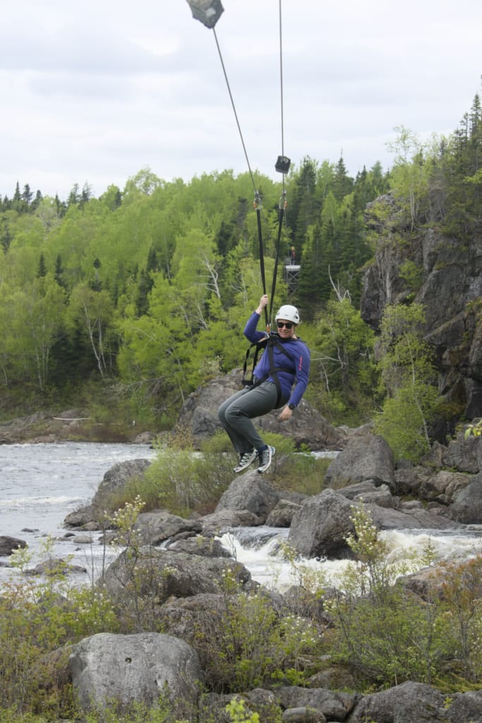 A woman ziplines across the Exploits River in Grand Falls-Windsor, NL