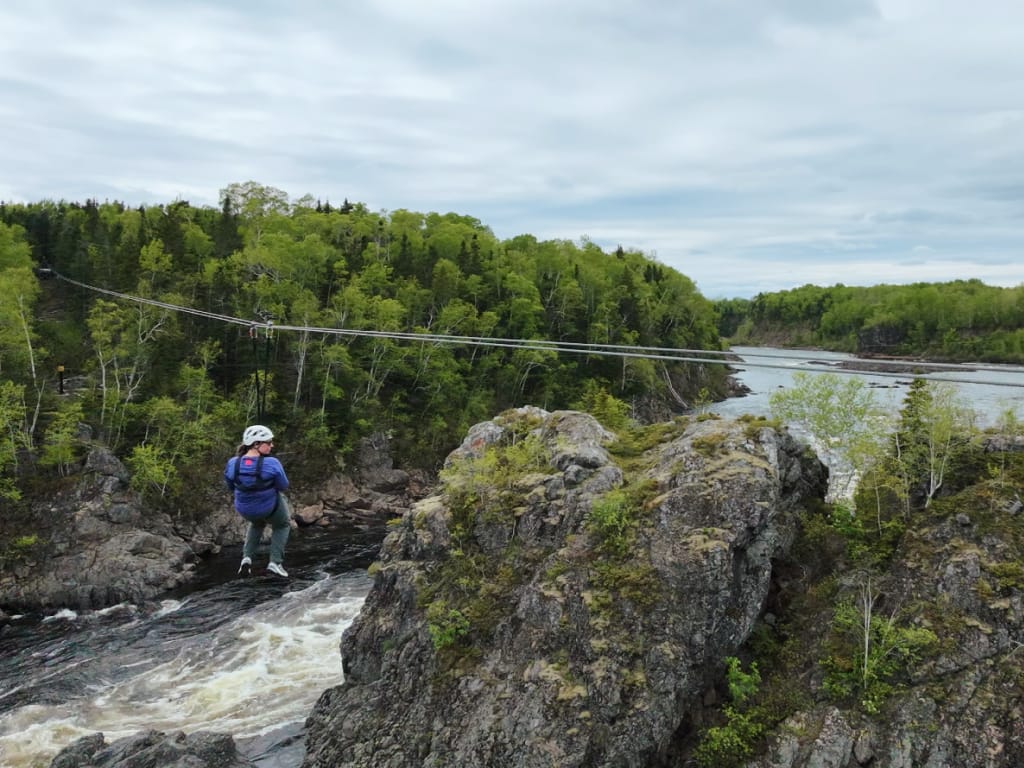 A woman ziplines across the Exploits River