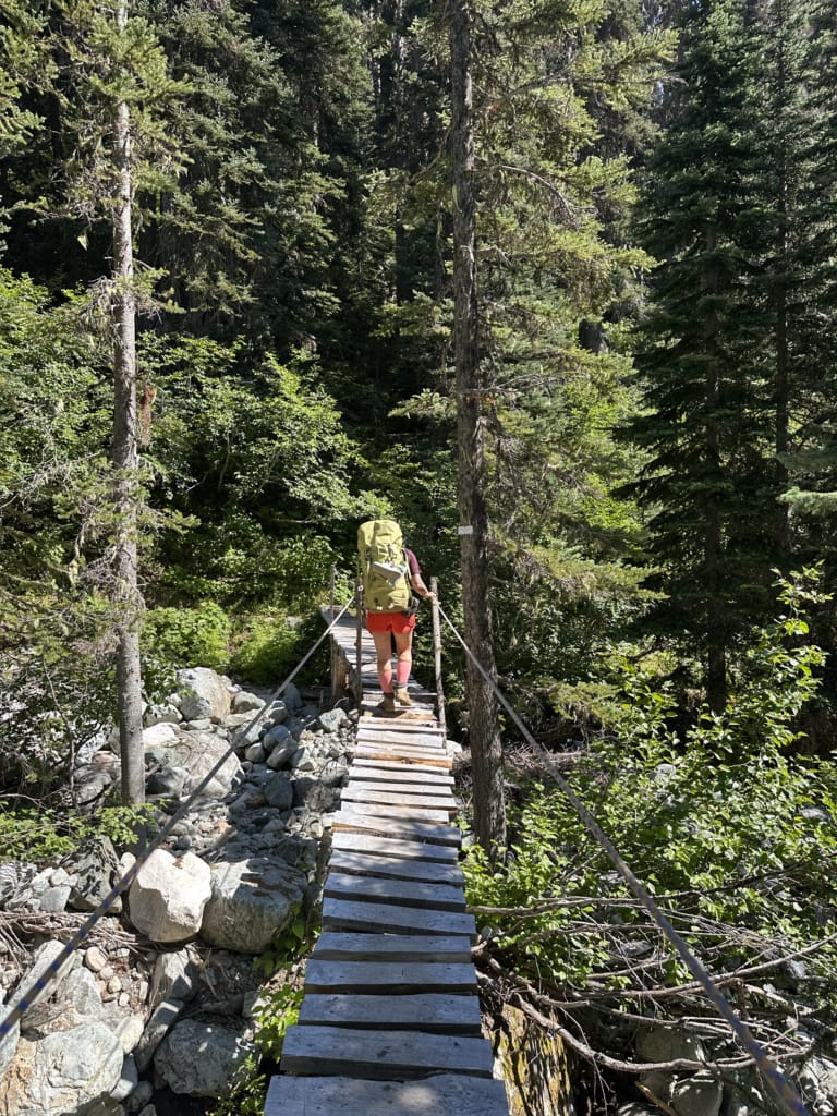A hiker crosses the bridge over Mowich Creek