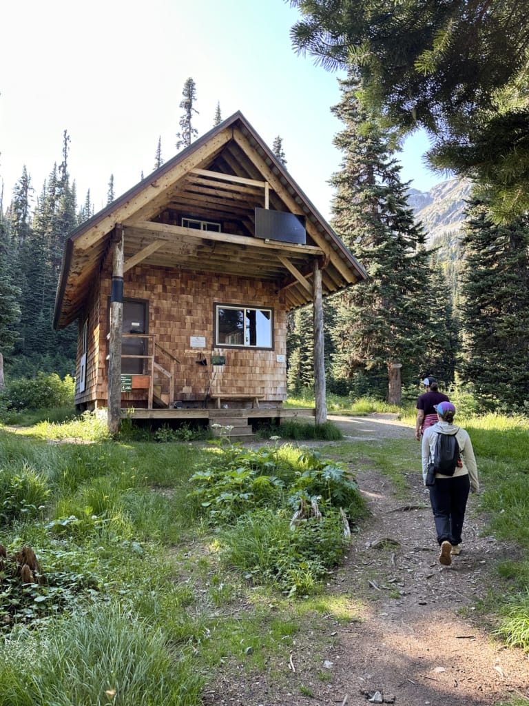 Hikers walk past the Tenquille Lake Cabin