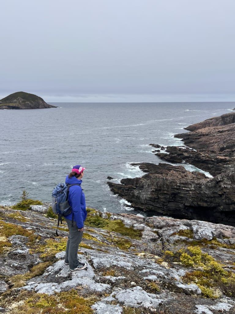 A hiker stands on a rocky coastline on the Damnable Trail in Salvage on the Eastport Peninsula