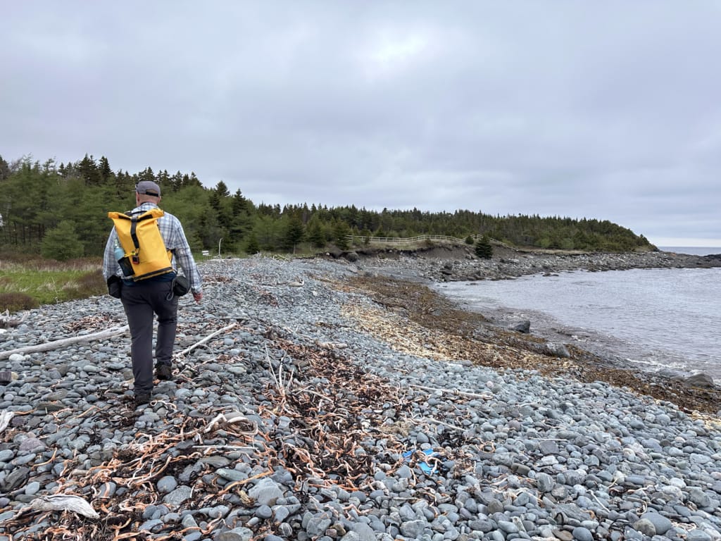 A hiker on the beach at Round Cove on the East Coast Trail near Cappahayden, Newfoundland