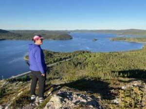 A woman stands on a rocky outcrop at Mill Cove Viewpoint in Terra Nova National Park near the Eastport Peninsula