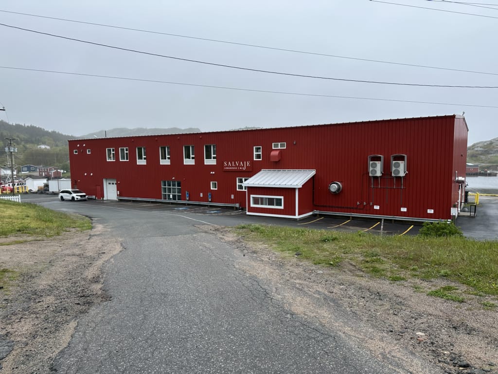 The exterior of the Salvaje Longhouse on the Eastport Peninsula in Newfoundland. It's a big red building that used to be a fish plant.