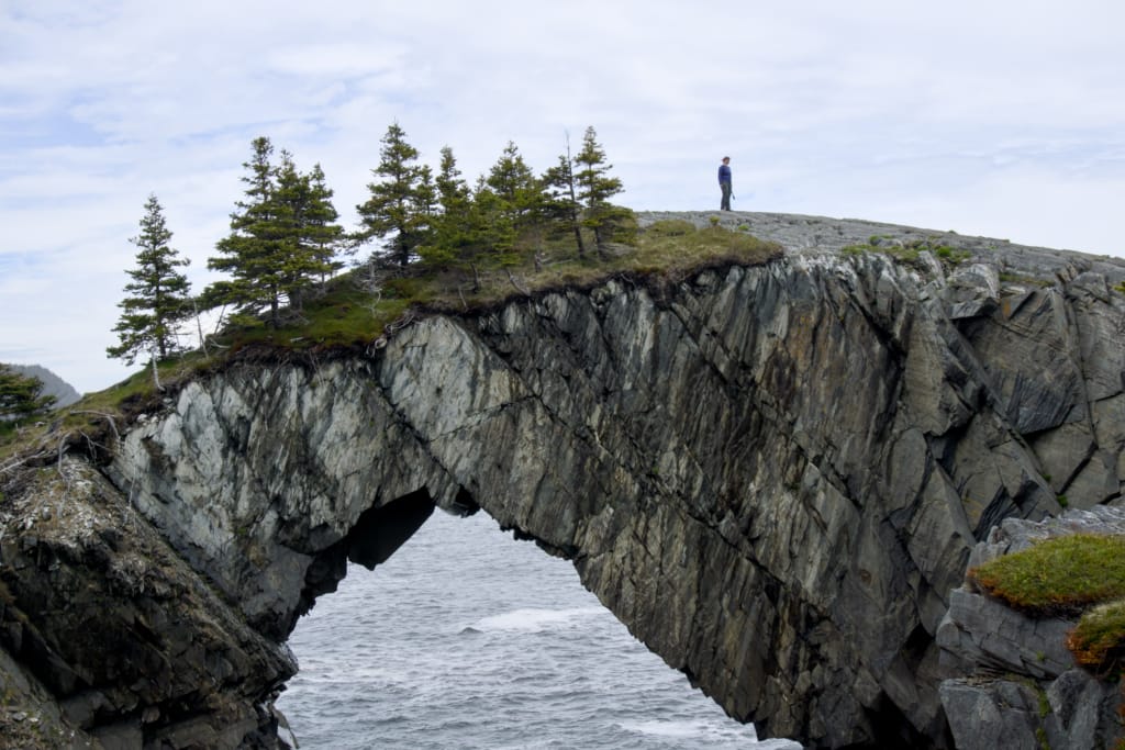 A hiker walking on top of Berry Head Arch on the East Coast Trail